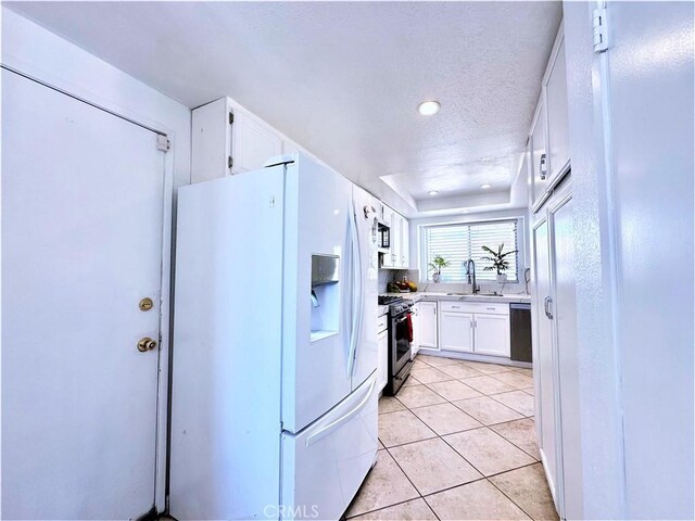 kitchen with a textured ceiling, white cabinetry, dishwasher, stainless steel gas range, and white refrigerator with ice dispenser