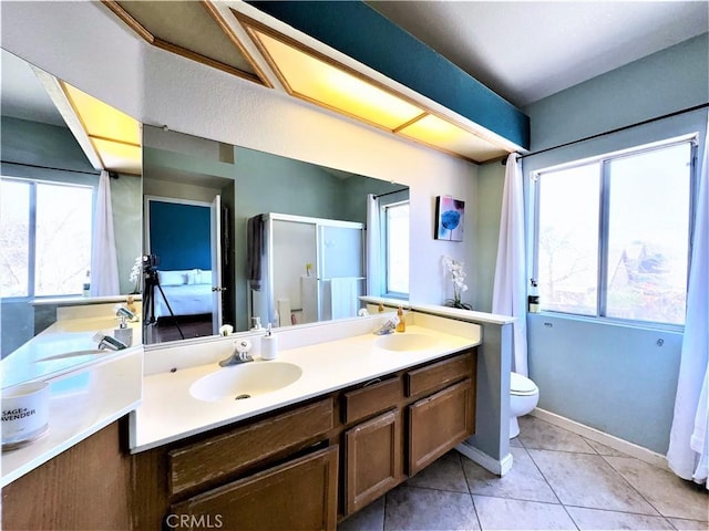 bathroom with toilet, tile patterned floors, a wealth of natural light, and vanity