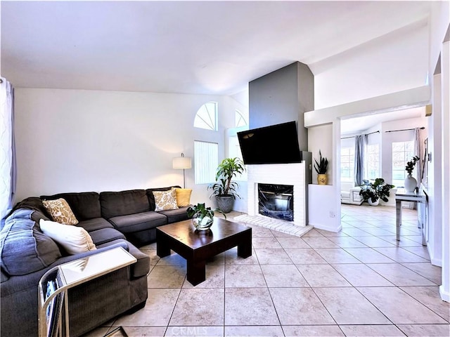 living room with a brick fireplace and light tile patterned floors