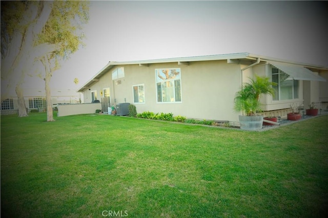 rear view of property featuring a yard and central air condition unit