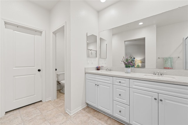 full bathroom featuring toilet, double vanity, a sink, and recessed lighting