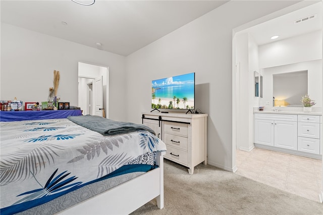 bedroom with light colored carpet, visible vents, a sink, ensuite bath, and baseboards