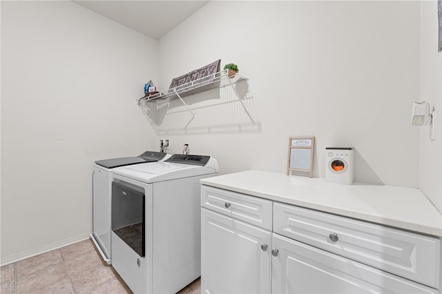 washroom featuring cabinet space, washer and clothes dryer, baseboards, and light tile patterned floors