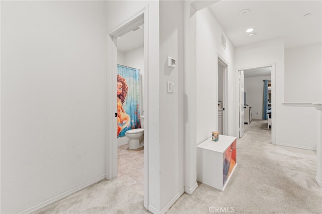 hall featuring light carpet, visible vents, and baseboards