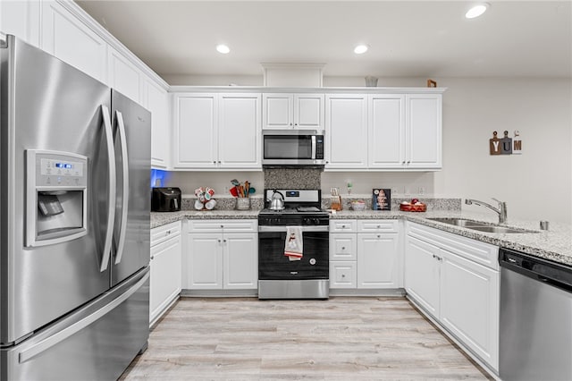 kitchen featuring stainless steel appliances, light wood finished floors, a sink, and white cabinets