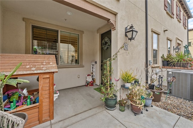 view of exterior entry featuring a patio area, central AC, and stucco siding