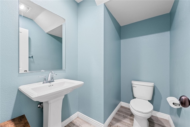 bathroom featuring visible vents, toilet, a sink, wood finished floors, and baseboards