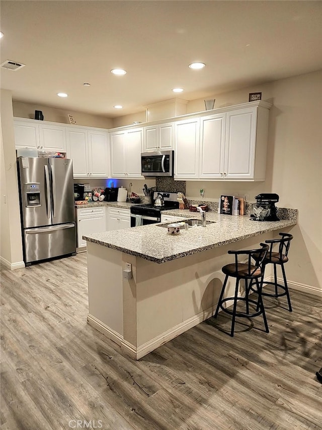 kitchen with stainless steel appliances, visible vents, white cabinets, and a peninsula