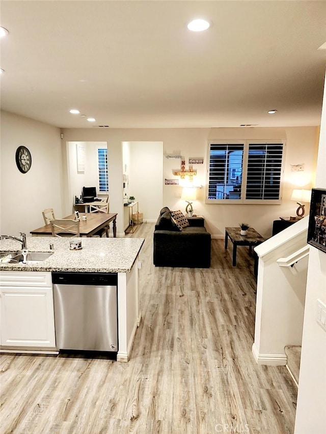 kitchen with dishwasher, light wood-style flooring, open floor plan, white cabinetry, and a sink