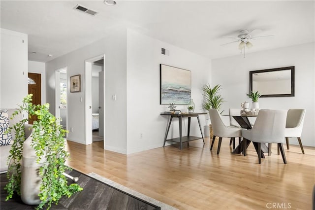 dining room featuring ceiling fan, light wood-style flooring, visible vents, and baseboards