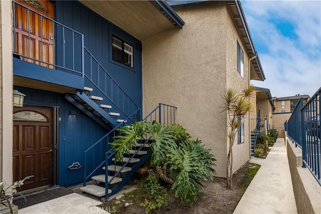 view of side of property featuring stairway and stucco siding