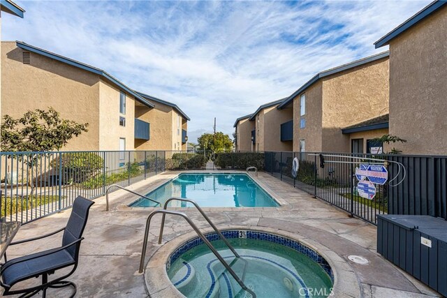 view of swimming pool with a hot tub