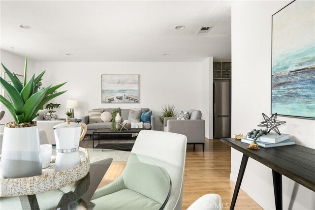 living area with light wood-style flooring, visible vents, and recessed lighting