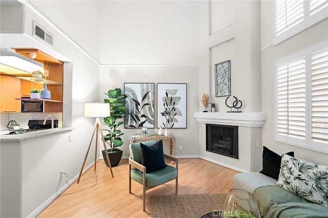 sitting room with a high ceiling and light hardwood / wood-style flooring