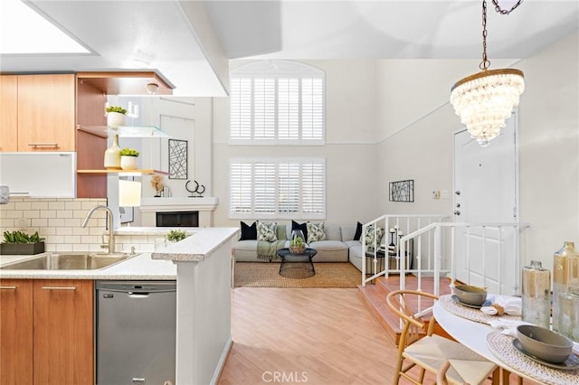 kitchen featuring decorative light fixtures, stainless steel dishwasher, decorative backsplash, sink, and an inviting chandelier