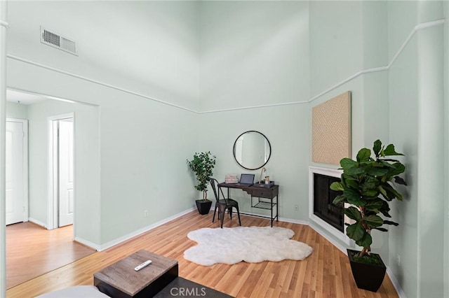 sitting room with a high ceiling and wood-type flooring