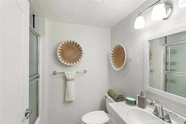 bathroom featuring toilet, vanity, and a shower with shower door