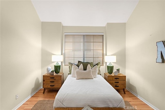 bedroom with vaulted ceiling and hardwood / wood-style flooring