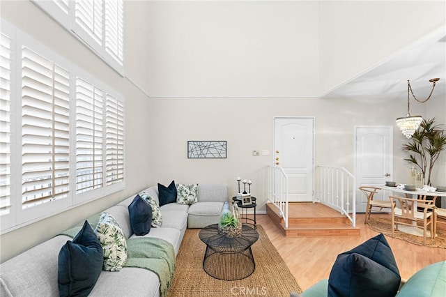 living room featuring a towering ceiling, a notable chandelier, and hardwood / wood-style flooring