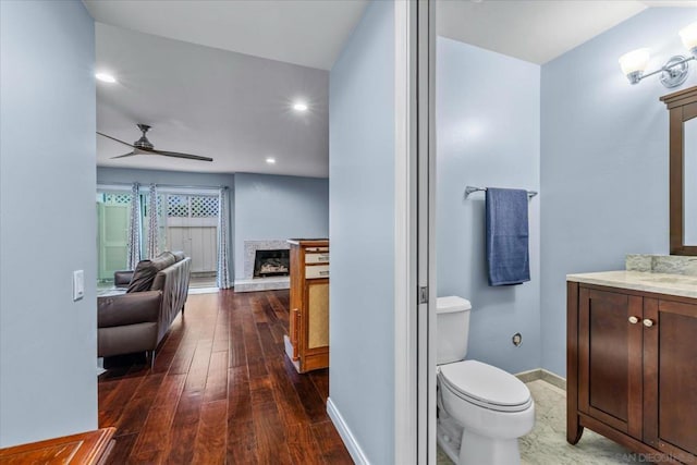 bathroom featuring toilet, ceiling fan, wood-type flooring, and vanity