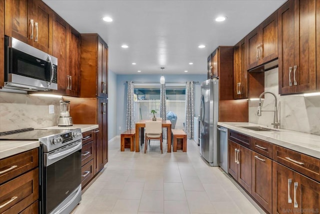 kitchen with backsplash, sink, light stone counters, and stainless steel appliances