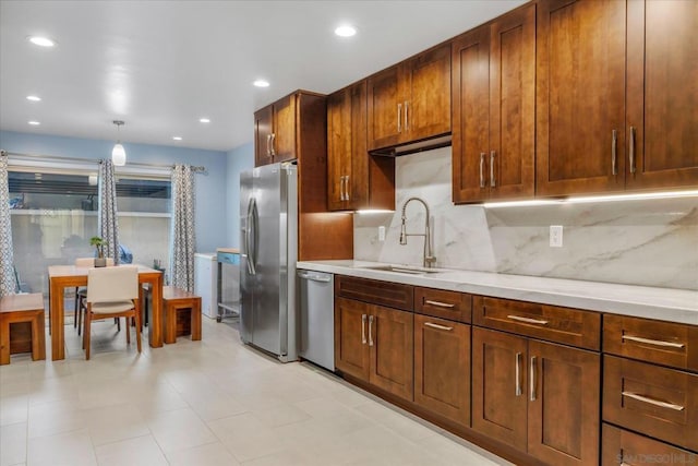 kitchen with appliances with stainless steel finishes, backsplash, decorative light fixtures, light stone counters, and sink