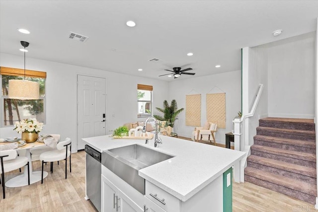 kitchen with pendant lighting, dishwasher, sink, white cabinets, and a kitchen island with sink