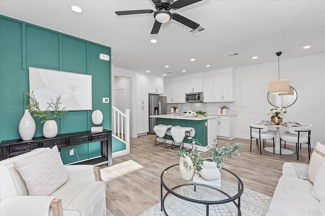 living room featuring sink, ceiling fan, and light wood-type flooring