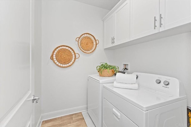 clothes washing area featuring separate washer and dryer, light hardwood / wood-style flooring, and cabinets