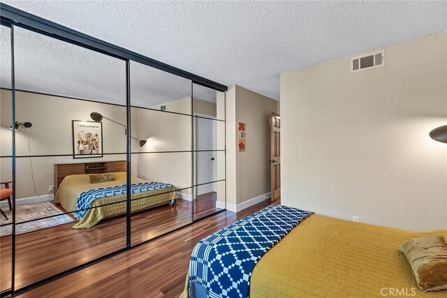 bedroom with a textured ceiling, a closet, and hardwood / wood-style floors