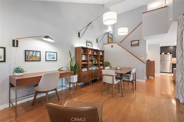 dining space featuring lofted ceiling with beams and light hardwood / wood-style flooring