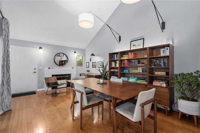 dining area with high vaulted ceiling, a fireplace, and hardwood / wood-style flooring