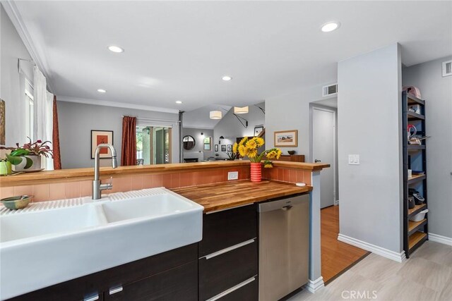 kitchen featuring dishwasher, light hardwood / wood-style floors, sink, crown molding, and butcher block counters