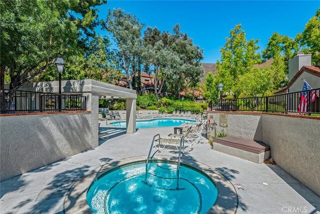 view of swimming pool with a patio area and a hot tub