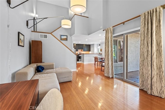 living room featuring an inviting chandelier, a towering ceiling, and light wood-type flooring