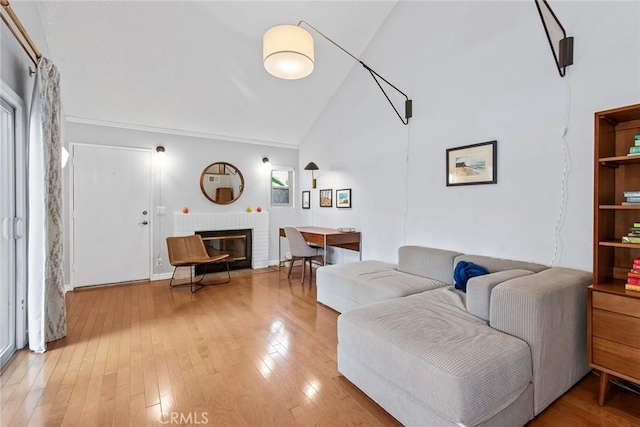 living room with hardwood / wood-style flooring, a brick fireplace, plenty of natural light, and high vaulted ceiling