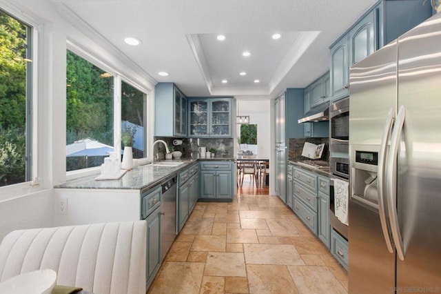 kitchen with appliances with stainless steel finishes, radiator heating unit, tasteful backsplash, sink, and a raised ceiling