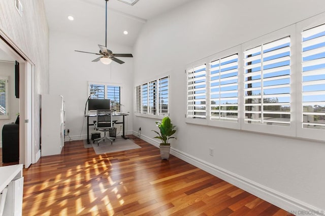 unfurnished office with ceiling fan, wood-type flooring, and high vaulted ceiling