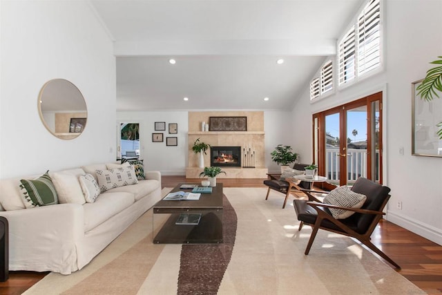 living room with hardwood / wood-style flooring, high vaulted ceiling, a tiled fireplace, and beamed ceiling