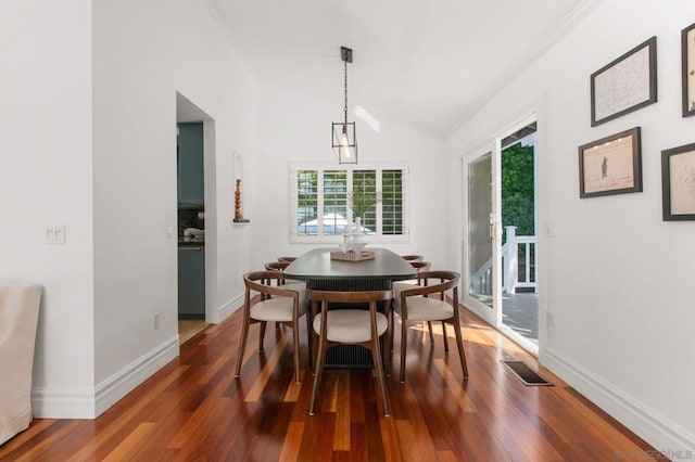 dining area featuring dark wood-type flooring, a notable chandelier, and vaulted ceiling