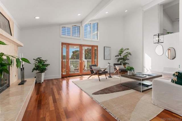 living room with beam ceiling, wood-type flooring, a high ceiling, ornamental molding, and french doors