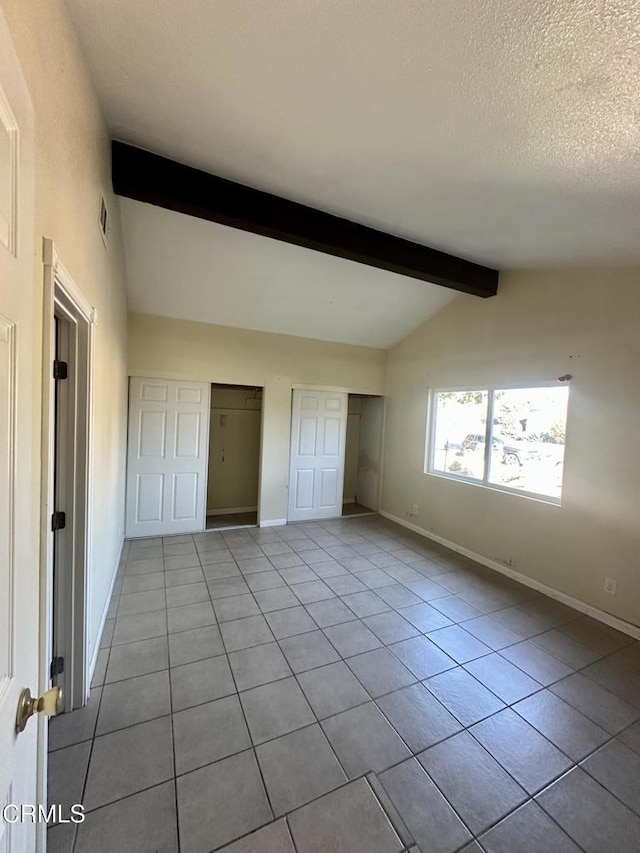 interior space with light tile patterned floors, lofted ceiling with beams, and a textured ceiling