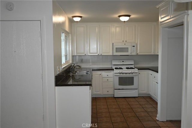 kitchen with sink, white cabinets, dark tile patterned floors, and white appliances