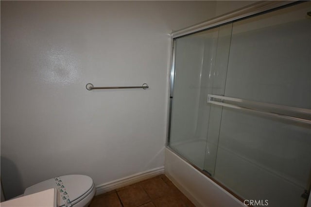 bathroom featuring toilet, enclosed tub / shower combo, and tile patterned flooring