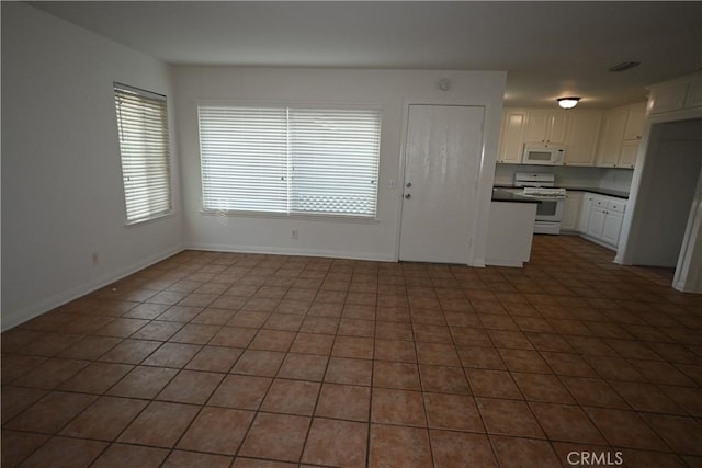 interior space featuring dark tile patterned flooring, white appliances, and white cabinetry