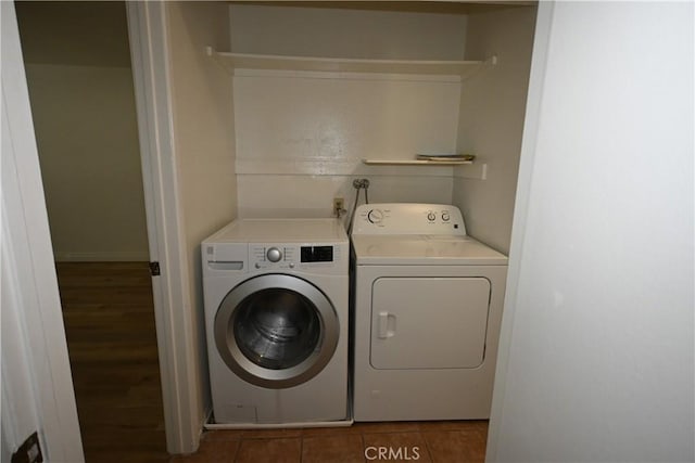 clothes washing area featuring washer and dryer and dark tile patterned flooring