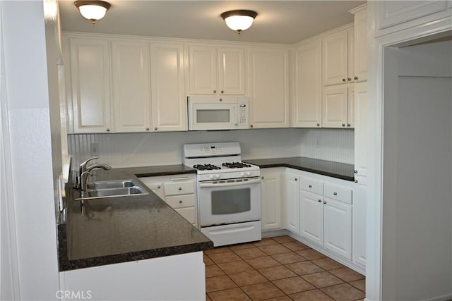 kitchen featuring white cabinetry, sink, white appliances, and dark tile patterned floors