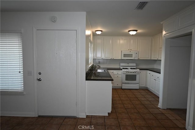 kitchen featuring sink, dark tile patterned flooring, white cabinets, and white appliances