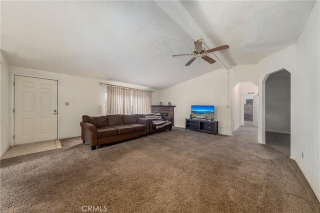 carpeted living room with ceiling fan, a textured ceiling, and vaulted ceiling with beams