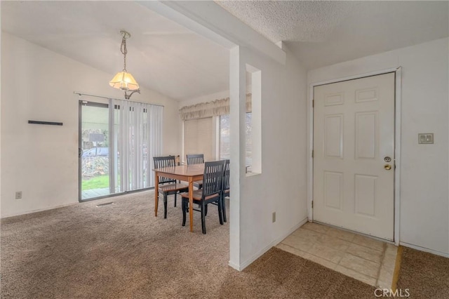 carpeted dining space featuring a textured ceiling and vaulted ceiling